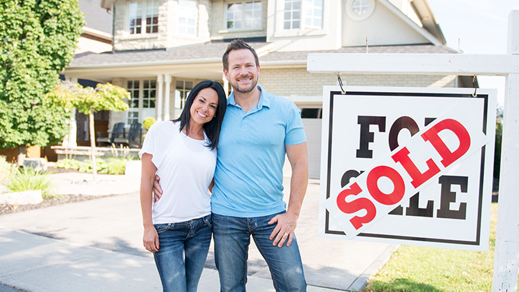selling real estate near camden ny smiling couple in front of home with sold sign from christmas country homes